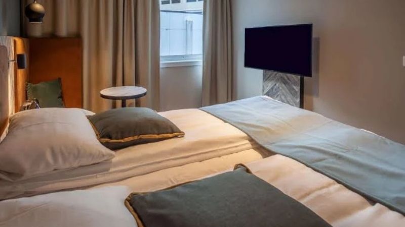 Modernt hotellrum på Scandic Harstad med dubbelsäng, stilren inredning, platt-TV och fönster som släpper in dagsljus – bekvämt boende i centrala Harstad, Nordnorge.